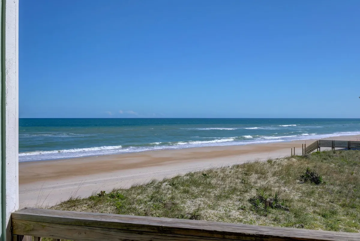 A stunning view of the ocean with a sandy beach, dunes, and blue sky. This tranquil scene directly connects with group beach outings, sunbathing, volleyball matches, and leisurely afternoons described in the section.